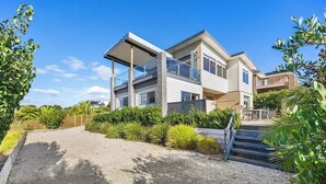 Une maison moderne à deux étages, avec une allée en gravier et une clôture en bois.