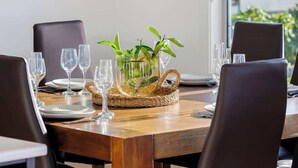 Une table à manger agrémentée d’un centre de table en fibres tressées, de verres transparents et d’assiettes.