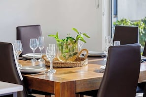 A dining table with a woven centerpiece, clear glassware, and plates. - Blissful Sunhill | Pool & Bay Views (Mount Martha)