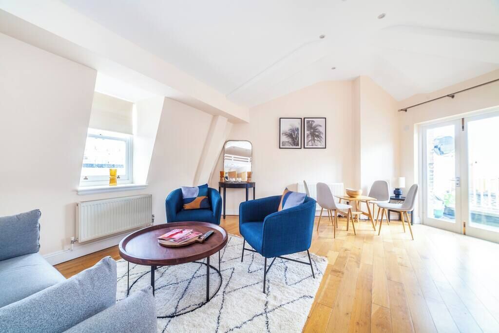Ein modernes Wohnzimmer mit Sofa, Sesseln, einem Couchtisch und einem Essbereich mit Stühlen und Tisch.