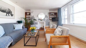 A modern living room with a sofa, armchair, coffee table, and bookshelf.