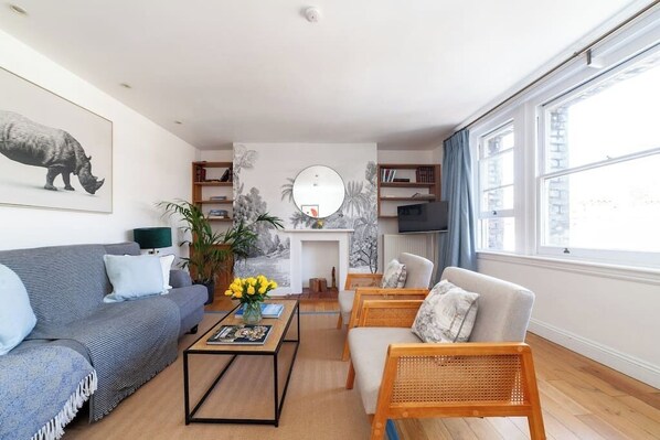 A modern living room with a sofa, armchair, coffee table, and bookshelf.