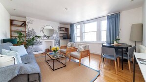 A modern living room with a sofa, armchairs, a coffee table, and a dining area.
