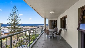 A balcony with a view of the ocean, a table with chairs, and a railing. - Gena Apartments Unit 14 Kings Beach QLD (Kings Beach)