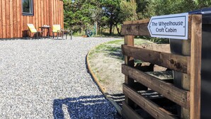 A wooden building labeled "The Wheelhouse Croft Cabin" with outdoor seating and a gravel path. - The Wheelhouse (Isle of North Uist)