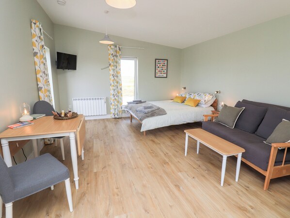 A room with a bed, a sofa, a table, and a chair. - The Wheelhouse (Isle of North Uist)