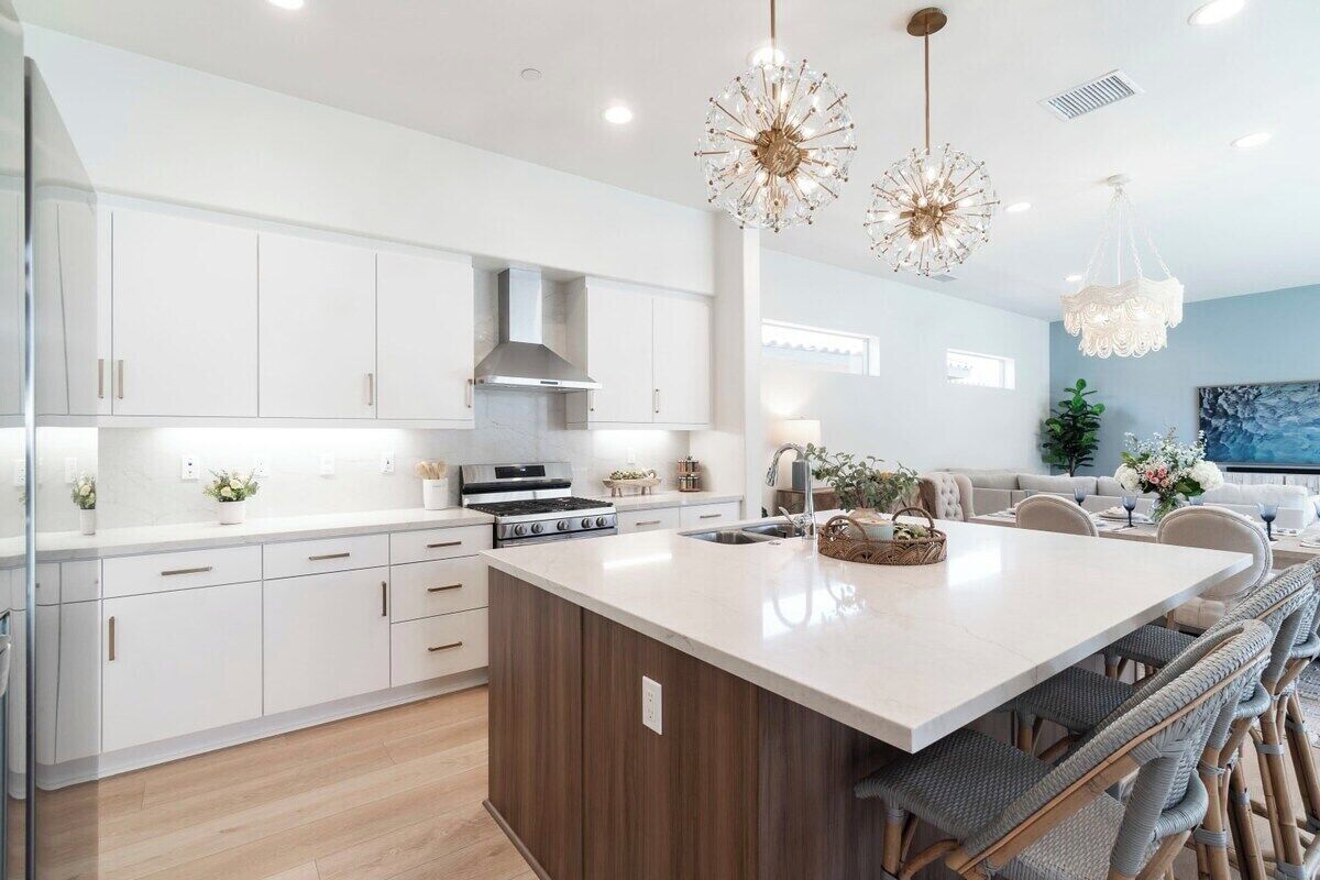 A modern kitchen with white cabinetry, a central island, and pendant lighting.