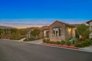 A residential property with a stone facade, a well-maintained lawn, and a clear view of the surrounding landscape. - Mountain Views, Poolside Bliss, PGA Golf & Spa (La Quinta)