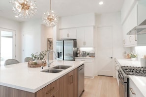 A modern kitchen with a central island, stainless steel appliances, and pendant lighting.
