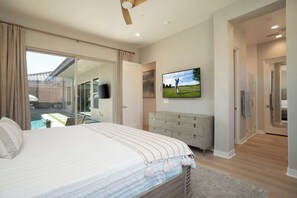 A bedroom with a large bed, a television, a dresser, and a sliding glass door leading to a balcony. - Mountain Views, Poolside Bliss, PGA Golf & Spa (La Quinta)