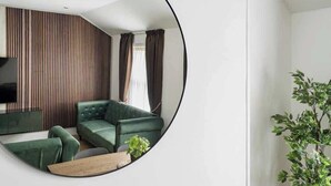 Ein modernes Wohnzimmer mit einem grünen Sofa, einem Fernseher und einem Holztisch.