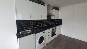 A modern kitchen with white cabinets, black countertops, and a built-in washing machine.