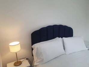 Relax in comfort with a neatly made bed and a bedside table featuring a lamp.