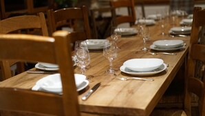 A wooden dining table set with white plates, glasses, and cutlery. - Moulin Proche Rivière Dans la Campagne Lotoise (Saint-Denis-Catus)