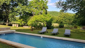 A swimming pool with lounge chairs and a hammock, surrounded by lush greenery and trees. - Moulin Proche Rivière Dans la Campagne Lotoise (Saint-Denis-Catus)