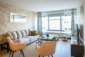 Una sala de estar moderna con un sofá, dos sillones, una mesa de centro y un mueble para televisor.