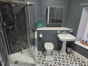 A bathroom with a shower, toilet, sink, and first aid kit.