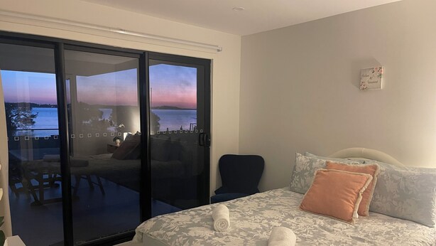 Une chambre à coucher avec un lit, des oreillers et une vue sur la mer, accessible par une porte coulissante.
