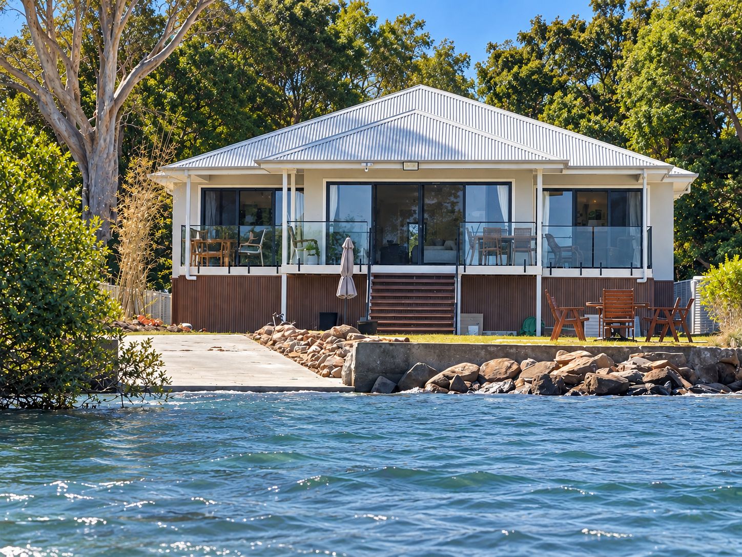 A modern house with a large balcony, a swimming pool, and a view of the water.