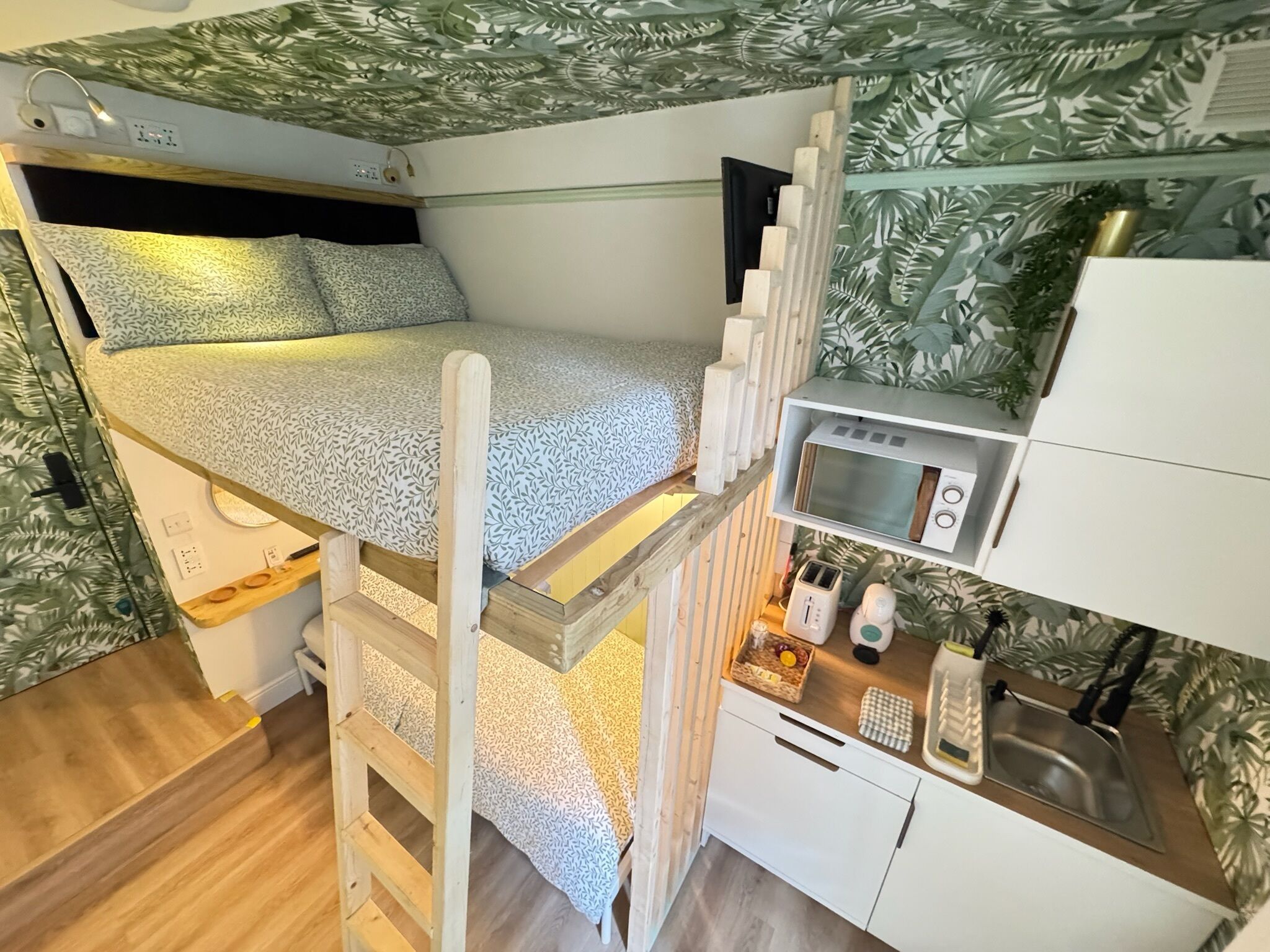 A compact room with a bunk bed, kitchenette, and a small dining area.