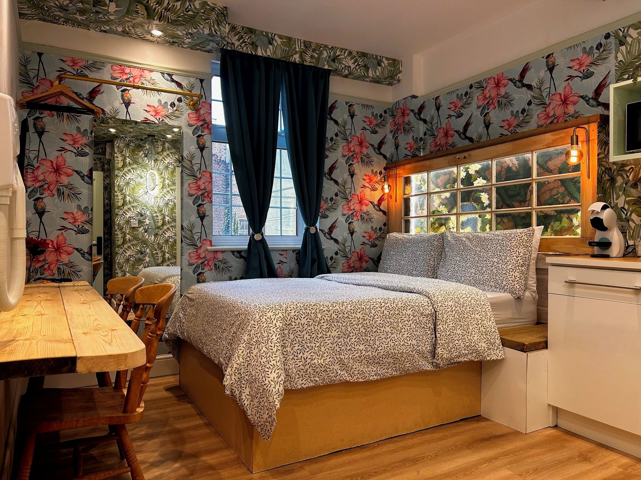 A bedroom with a bed, a desk, and a window with curtains.