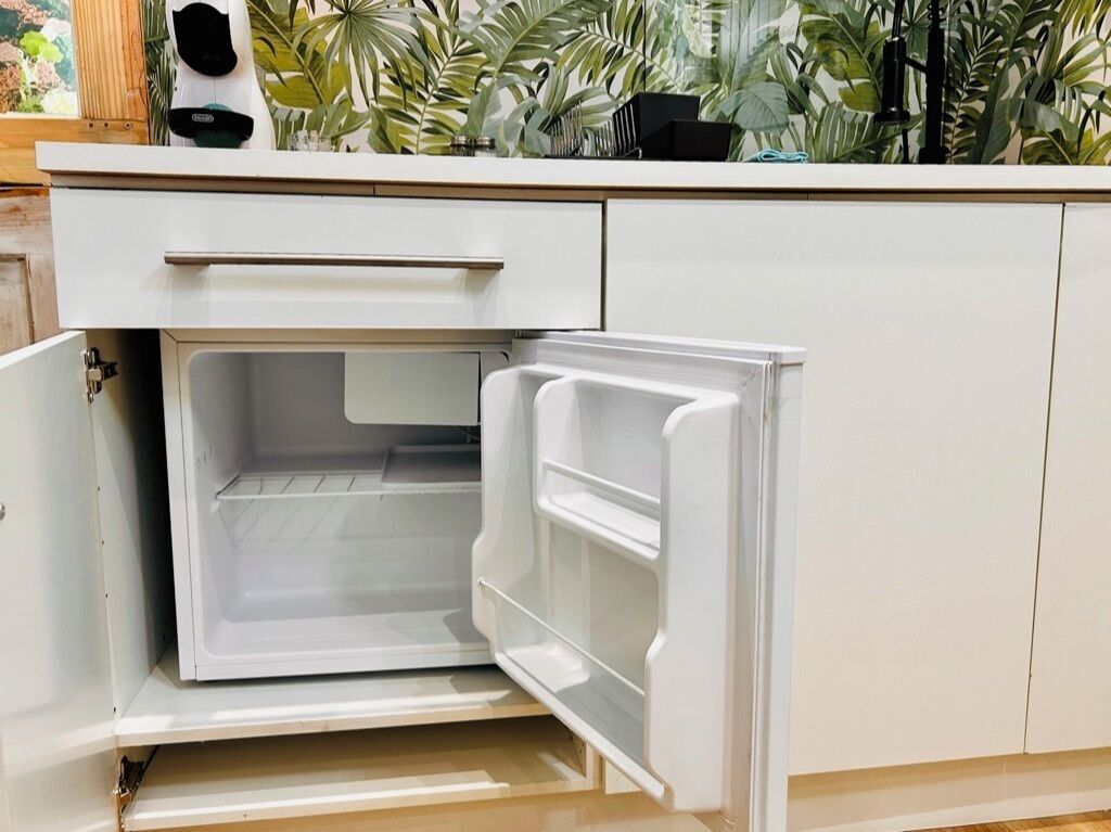 A kitchen with a white refrigerator, a white countertop, and a drawer.