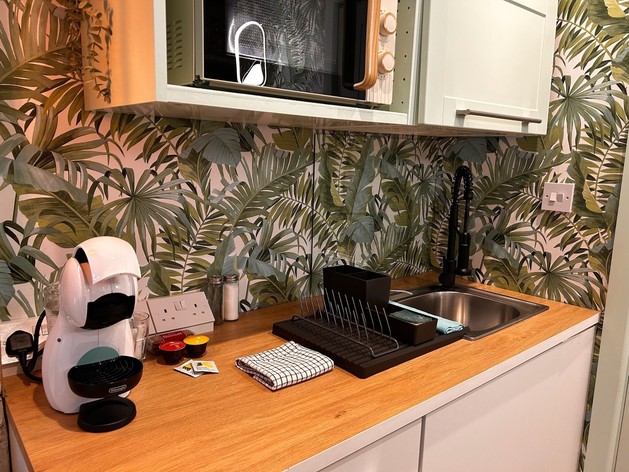 A kitchen with a microwave, coffee machine, and a sink.