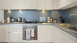 Eine moderne Küche mit hellen Schränken, einem Backofen, einer Spüle und verschiedenen Küchengeräten.
