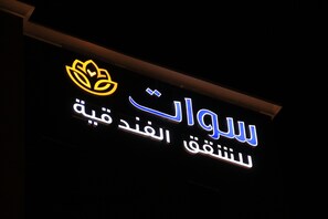 A hotel sign with Arabic text and a lotus flower logo.