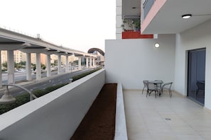 A balcony with a view of a road and buildings, a small table with chairs, and a door. - Stylish 1BR in Azizi Iris, Al Furjan (Dubai)