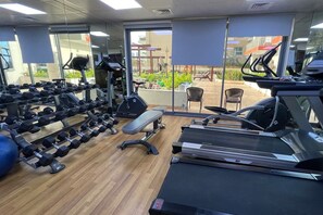 A gym with exercise equipment, a treadmill, and a bench. - Stylish 1BR in Azizi Iris, Al Furjan (Dubai)
