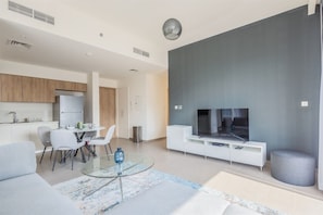 Ein modernes Wohnzimmer mit einem Glastisch, einer Couch und einem Flachbildfernseher.