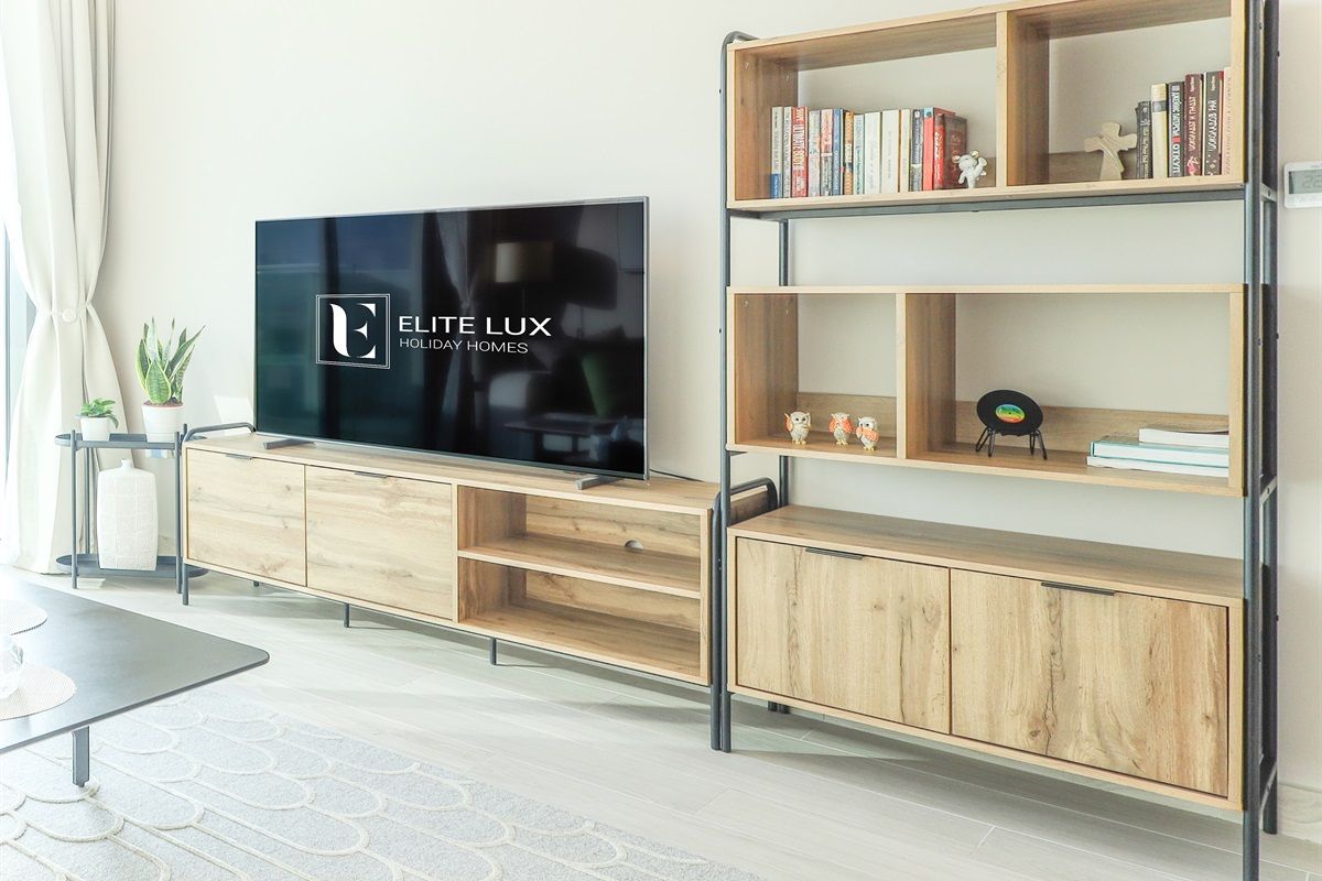 Un salon moderne doté d’un téléviseur à écran plat, d’étagères en bois et d’un design minimaliste.
