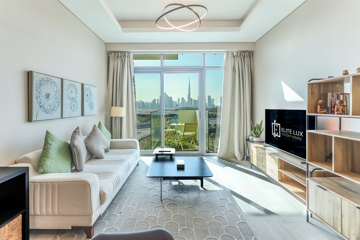 A modern living room with a sofa, coffee table, and TV, featuring a city view through large windows.