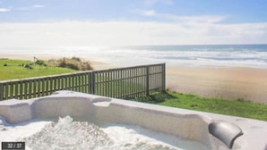 A beach view with a concrete structure, a wooden fence, and a grassy area. - Beach Me! Oceanfront steps2sand (Lincoln City)