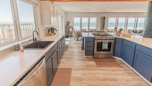 A modern kitchen with a large island, stainless steel appliances, and a view of the ocean. - Beach Me! Oceanfront steps2sand (Lincoln City)