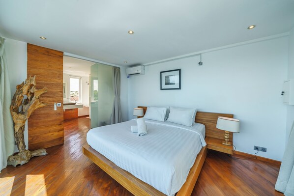 A modern hotel room with a large bed, wooden flooring, and a unique wooden wall feature. - Villa Tykhe (Seminyak)