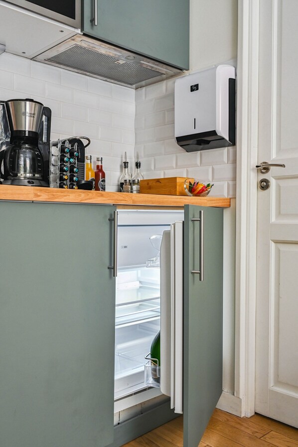 Una cocina con refrigerador empotrado, cafetera y dispensador de jabón en la encimera.