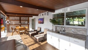 Cocina moderna con armarios blancos, un ventanal grande y techo de madera.