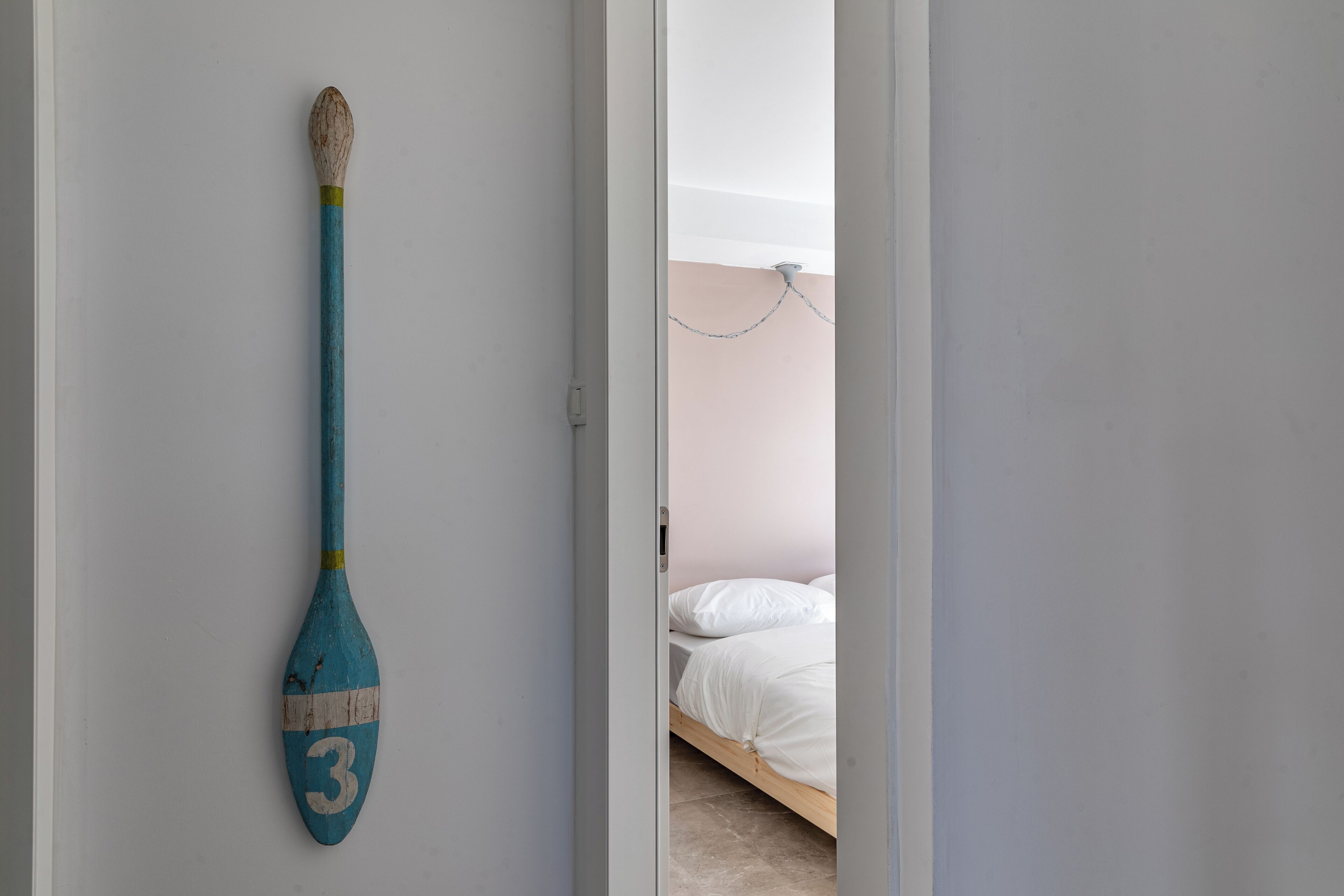 A room with a bed, a door, and a blue paddle with the number 3 on it.