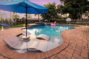 Ein Swimmingpool mit blauem Sonnenschirm, Liegestühlen und einem Flamingo-Schwimmpunkt.