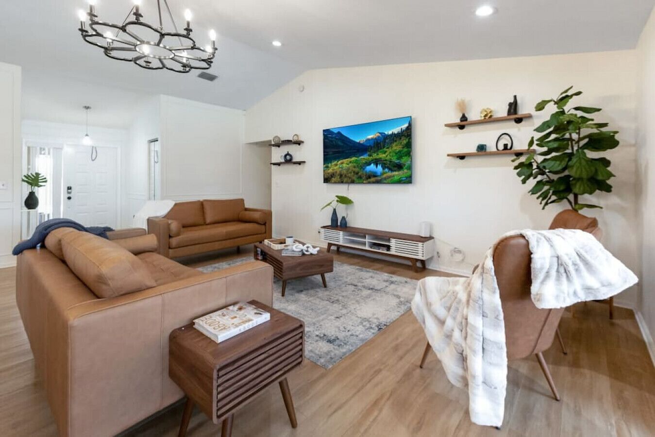 A modern living room with a brown sofa, a wooden coffee table, and a large painting on the wall.