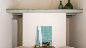 A room with two pink armchairs, a small black table, and a sewing machine on a wooden table. - Dimora SIQU (Menfi)