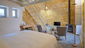 A bedroom with a large bed, a desk, two chairs, a TV, and a fireplace. - Dimora SIQU (Menfi)