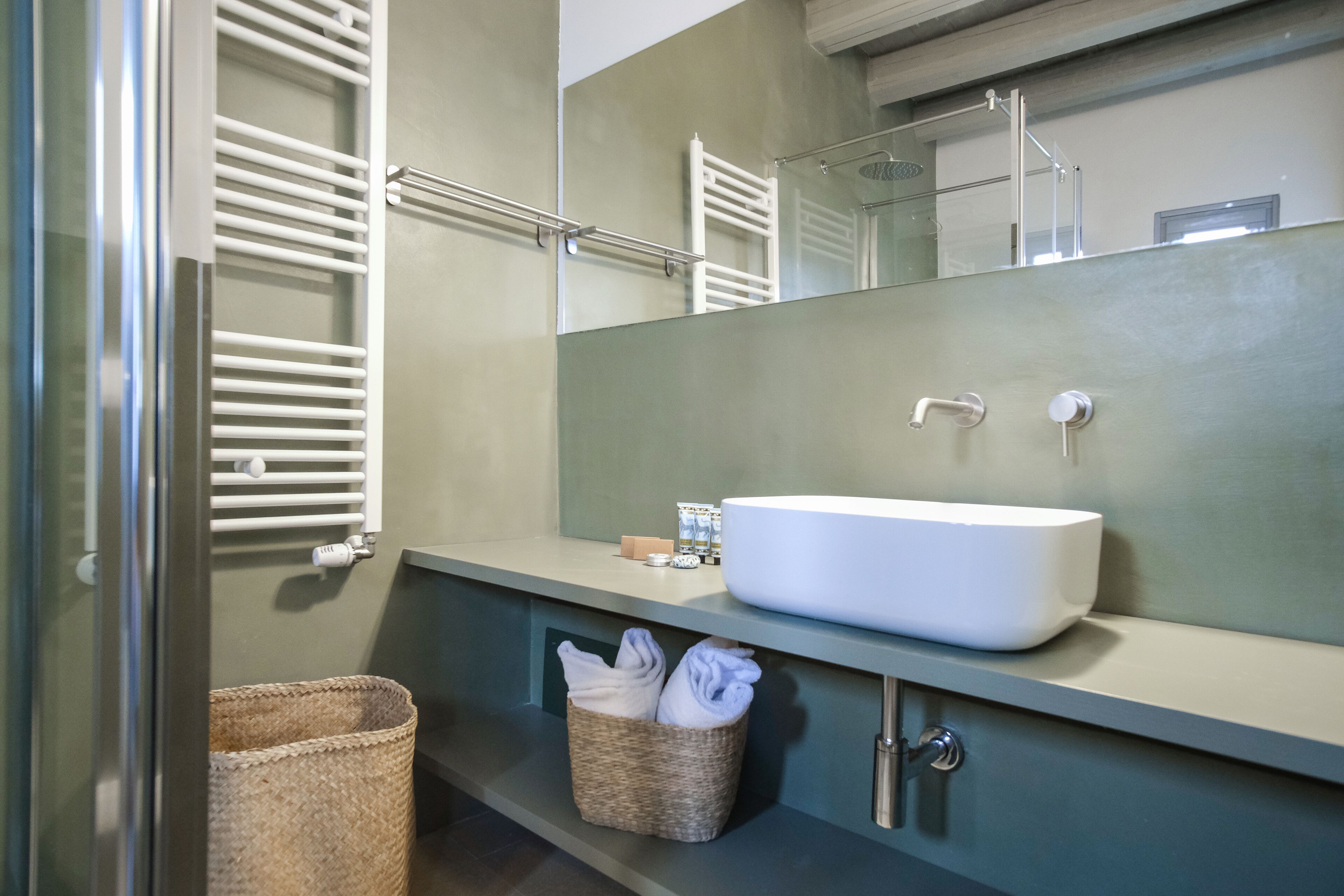 A bathroom with a white sink, a mirror, a towel rack, and a wicker basket.