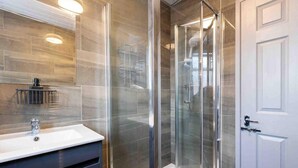 A modern bathroom with a glass-enclosed shower, a white sink, and a mirror above the sink.