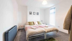 A bedroom with a bed, a radiator, a window with blinds, and a hanging towel.