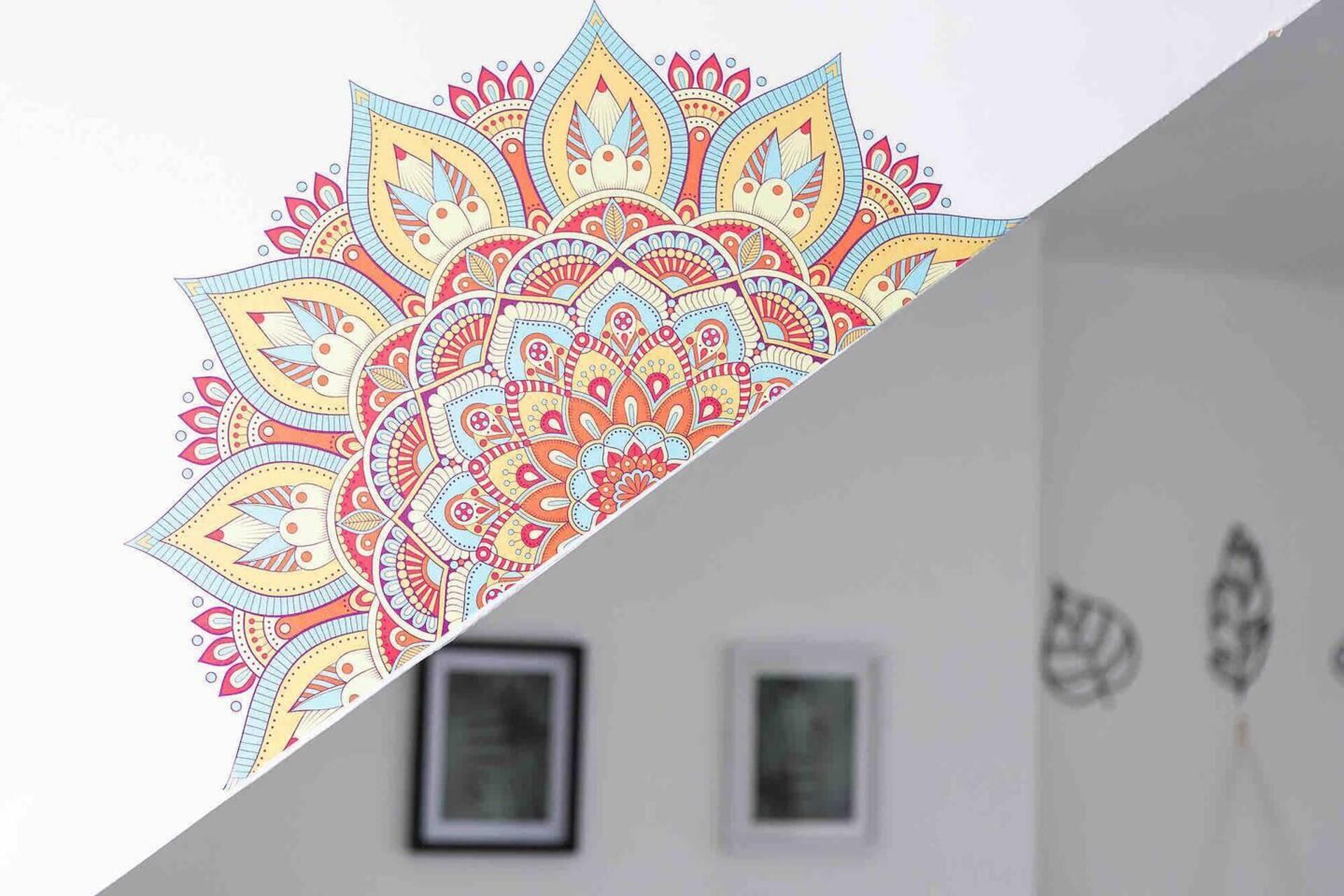 A room with a white wall, two framed pictures, and a colorful abstract design on the wall.