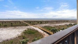 Blick auf die Küste vom Balkon aus, mit einem hölzernen Steg, der zum Strand führt.