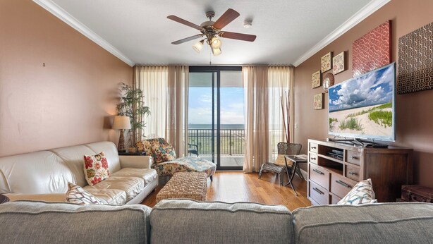 Ein Wohnzimmer mit Sofa, Ottoman, Fernseher und Deckenventilator.